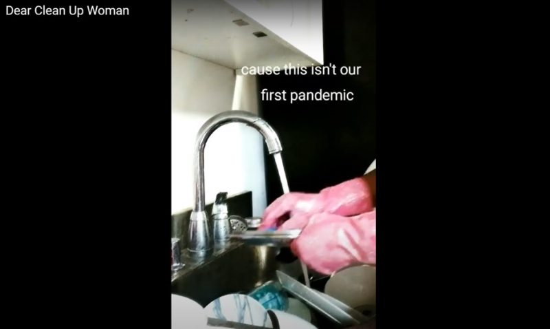 A screenshot of the work Breathing While Black, depicting a person wearing pink gloves washing their hands at a kitchen sink