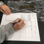 image shows close up of a sheet of paper and a student's hand; the student is completing an assignemnt of making a core description