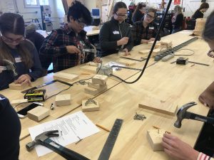 Cadette Girl Scouts learn woodworking skills like hammering.