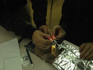 Students explore how to make light bulbs turn on by only using a D size battery, aluminum foiled and tiny light bulbs. NO WIRES!!!